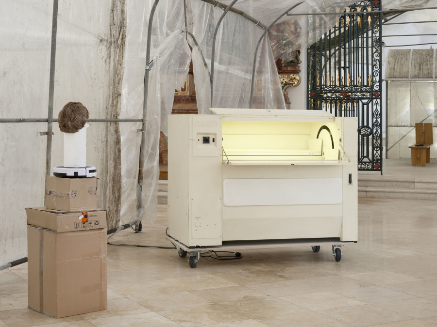 Left: Benedikt Bock, What People Want is Not What People Need (Günther), 2023. Cardboard, plaster, clay, wood, wig, glasses, 160 x 43 x 43 cm. Right: Thomas Julier & Max Kriegleder, itself, 2024. Automated filing cabinet, 60 x 80 x 100 cm. Photo credit: Sebastian Verdon / Abbatiale Bellelay