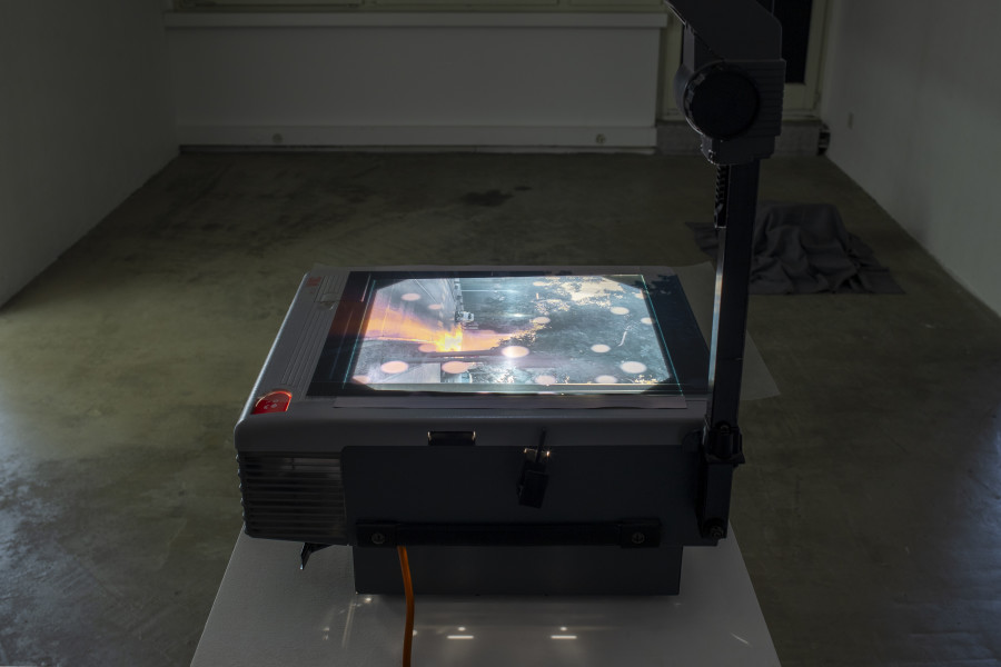 Exhibition view, Memory Mold, HAMLET, 2024. Front: Medjid Sopi, Front Seat, 2024, Digital print on PVC (A3), overhead projector; Back: Luca Büchler, Untitled, 2024, Fabric, artworks found at Hamlet by Sven Gex, Leevi Toija, Bleed, Dominic Michel, Benedikt Bock, Virginia Ariu, Vinzenz Meyner, Johanna Kotlaris, Lea Rüegg. Photo by Leevi Toija