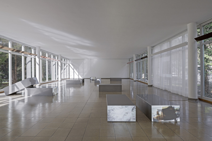 Nolan Lucidi, Bildersaal, Installation view Kunsthaus Glarus. Photo: Gina Folly, Kunsthaus Glarus 2026. Screening Sculpture (1–10), 2026, 10-Kanal-HD-Videoinstallation, Ton, verschiedene Längen zwischen 00:48 Min. und 26:37 Min., Loop, Gel-Transfer, Papierreste, Rückprojektionsfolie, Vorhang, Edelstahl. Metallobjekte jeweils 70 × 40 × 140 cm. Views (Loveroom 1-6), 2026, Bronze- und champagnerfarbene, verspiegelte Anti-Voyeur-Folie auf der Einfassung der Leuchten. 448,5 × 18,6 cm, 420 ×18,6 cm. Courtesy the artist