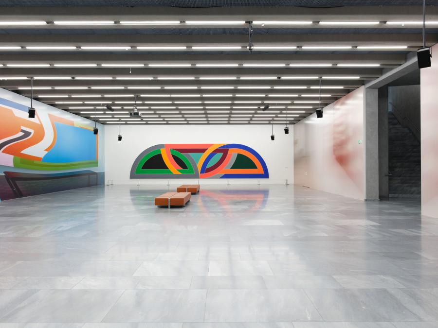 Exhibition view, Louise Lawler, Kunstmuseum Basel, 2024-2026. Three Flags (swiped and taken) (adjusted to fit) (mirrored or flipped) Cease Fire, Louise Lawler, Basel, Kunstmuseum, Neubau, Louise Lawler - Sammlungspräsentation, UG, Raum 4, 28.05.2024, 2022/2024, Adhesive wall material, Text: Dimensions variable to match proportions of a given wall at any scale determined by exhibitor - twice and once inverted. Courtesy the artist and Sprüth Magers. Kunstmuseum Basel, Zugesagte Schenkung. (Bunny) Sculpture and Painting (adjusted to fit, distorted for the times), Louise Lawler, Basel, Kunstmuseum, Neubau, Louise Lawler - Sammlungspräsentation, UG, Raum 4, 28.05.2024, 1999/2015/2019, Die Masse sind flexibel, so dass sie den Proportionen einer vom Ausstellenden gewählten Bestandswand beliebigen Massstabs entsprechen, Text: Dimensions variable to match proportions of a given wall at any scale determined by exhibitor. Courtesy the artist and Sprüth Magers. Kunstmuseum Basel, Ankauf mit Mitteln aus dem Ankaufskredit. Damascus Gate. Variation I, Frank Stella, Basel, Kunstmuseum, Neubau, Louise Lawler - Sammlungspräsentation, UG, Raum 4, 28.05.2024, 1969–1970, Acryl auf Leinwand, 304.5 x 1220 x 8 cm. © 2024, ProLitteris, Zurich. Kunstmuseum Basel, Ankauf. Photo credit: Max Ehrengruber