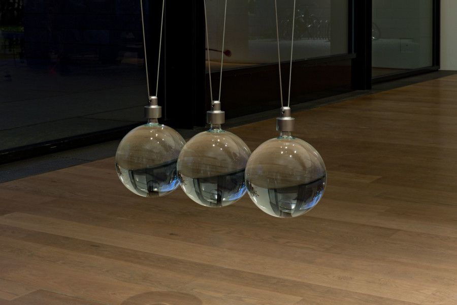 Katja Aufleger, NEWTON’S CRADLE, 2013/2020 Installation view «Katja Aufleger. GONE» with Jean Tinguely, Klamauk, 1979 (in the background)  Glass, steel, sulphuric acid, nitric acid, glycerine, rubber Dimensions variable ​​​​​​​© Courtesy of the artist; Galerie STAMPA, Basel; Museum Tinguely, Basel Hamburg; photo: Gina Folly