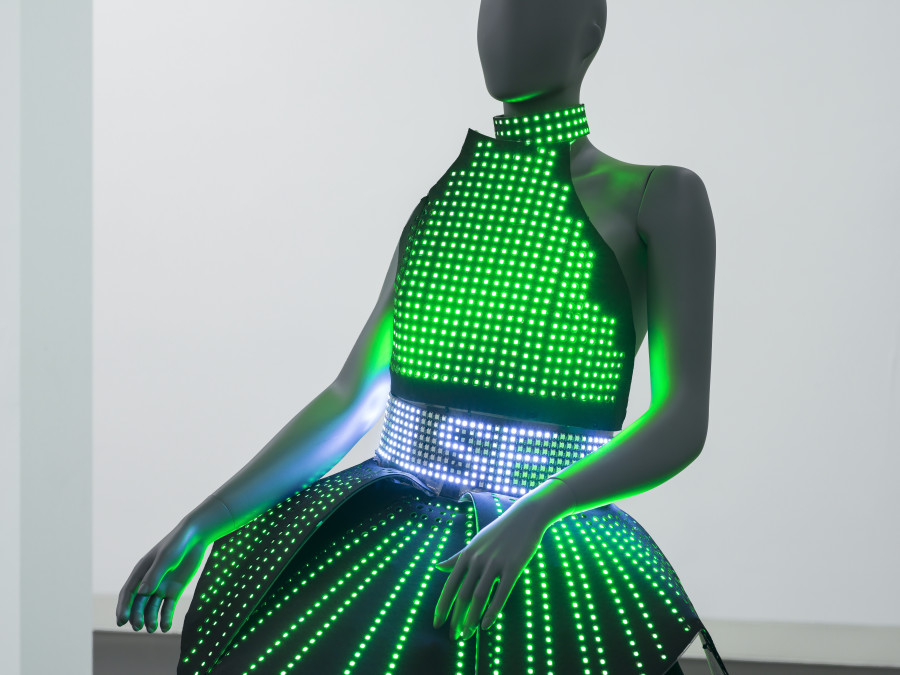 Puppies Puppies (Jade Guanaro Kuriki-Olivo), Electric Dress (Atsuko Tanaka), 2023, LED-dress made from textile and plastic, draped on mannequin, 12 lithium-ion batteries in cases in textile pockets, Madrix programmed micro SD-card, performance (optional), Dress 81 × 66 × 63 cm