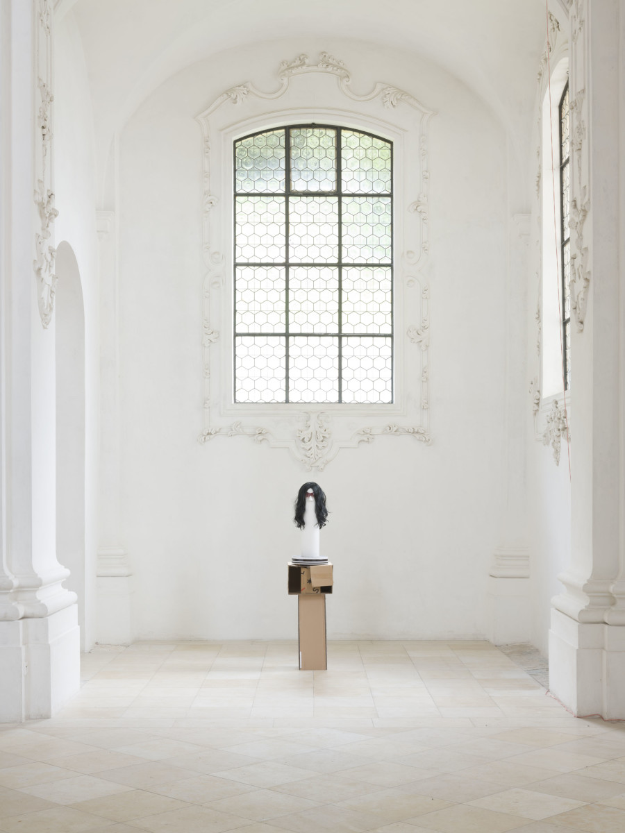 Benedikt Bock, What People Want is Not What People Need (Kim), 2023. Cardboard, plaster, clay, wood, wig, glasses, 175 x 40 x 40 cm. Photo credit: Sebastian Verdon / Abbatiale Bellelay