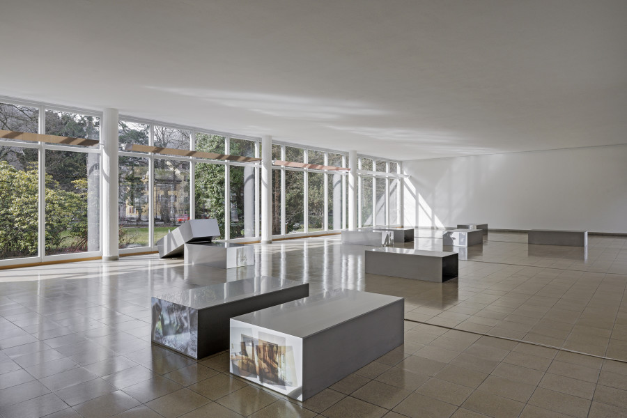 Nolan Lucidi, Bildersaal, Installation view Kunsthaus Glarus. Photo: Gina Folly, Kunsthaus Glarus 2026. Screening Sculpture (1–10), 2026, 10-Kanal-HD-Videoinstallation, Ton, verschiedene Längen zwischen 00:48 Min. und 26:37 Min., Loop, Gel-Transfer, Papierreste, Rückprojektionsfolie, Vorhang, Edelstahl. Metallobjekte jeweils 70 × 40 × 140 cm. Views (Loveroom 1-6), 2026, Bronze- und champagnerfarbene, verspiegelte Anti-Voyeur-Folie auf der Einfassung der Leuchten. 448,5 × 18,6 cm, 420 ×18,6 cm. Courtesy the artist