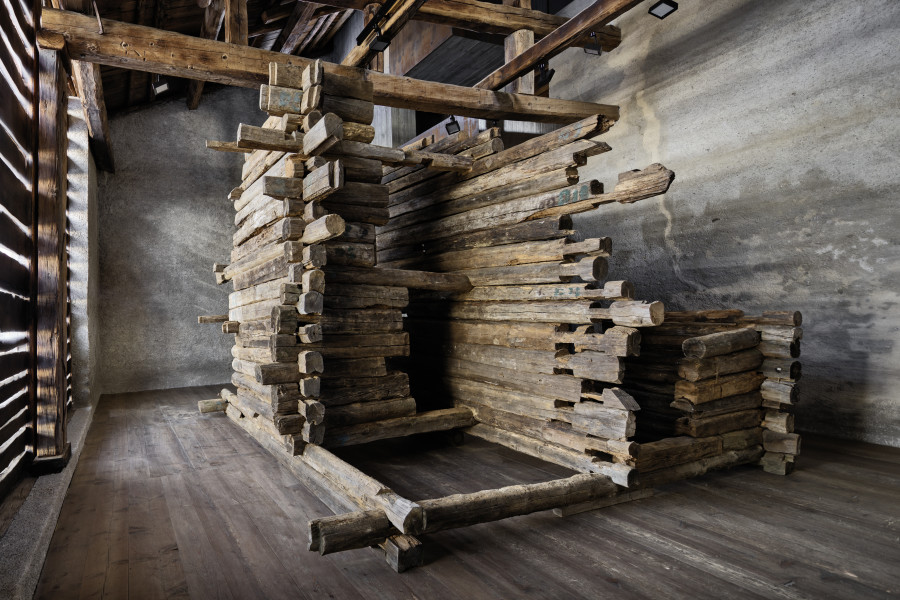 Exhibition view, Augustas Serapinas, Remains of the House from Skirgiškės, 2022, reclaimed wood, 370 x 480 x 500 cm. Photo: Ralph Feiner, Courtesy of the artist and Galerie Tschudi